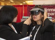 a woman who is visually impaired trying on a headset imaging device at the CSUN conference