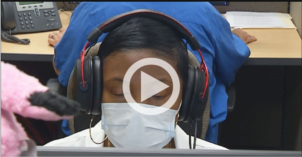 Image of Sophia in the call center at her computer wearing a protective mask - click to watch the news story on Spectrum's site