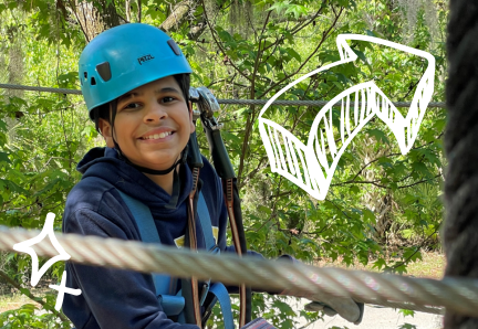 100 A young person wearing a safety helmet and harness smiles while participating in an outdoor ropes course.