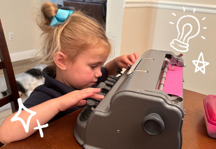 25 A young child sits at a table using a braille typewriter, concentrating on the keys.