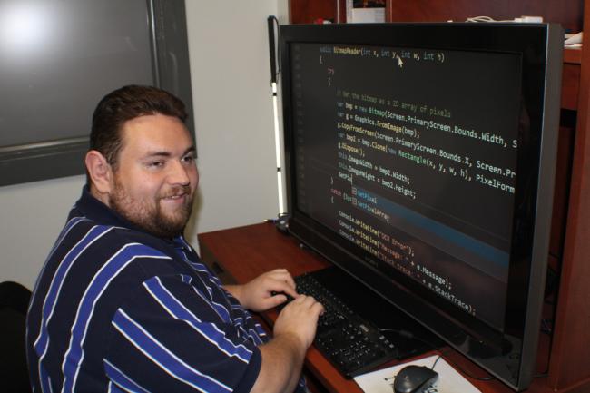 Mike Fox, Lighthouse Works Software designer and accessibility expert, at his computer working on some code using a screen magnifier 