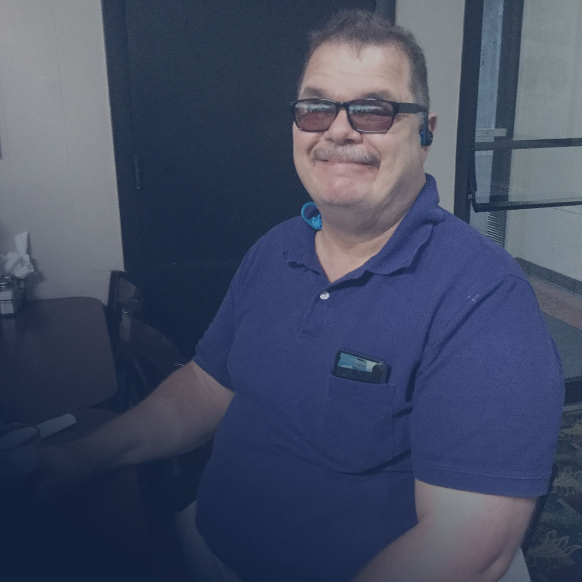 image of Lighthouse employee, Fred, smiling while sitting at his desk