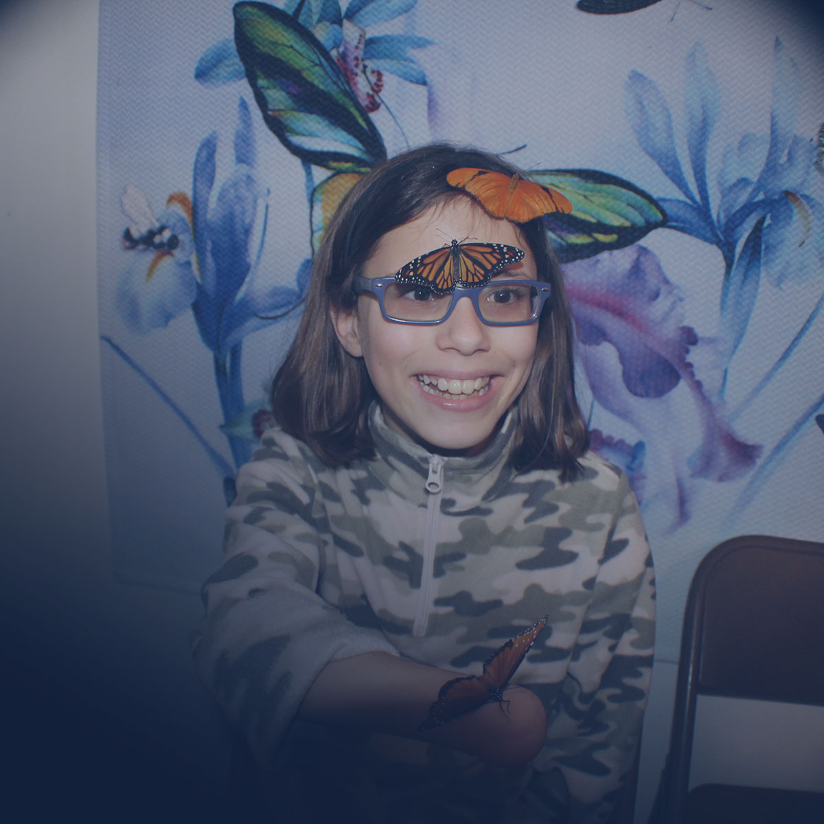 Image of Lighthouse client, Grace, interacting with butterflies on one of the student field trips to Butterfly Dan's